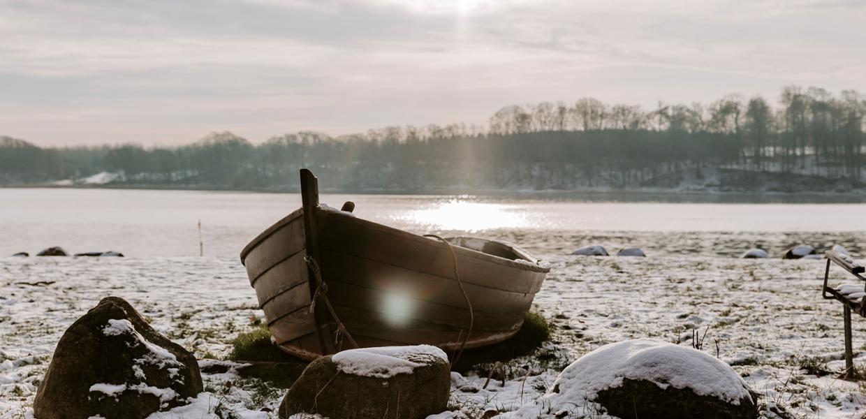 Solstråler rammer den lille jolle i strandkanten