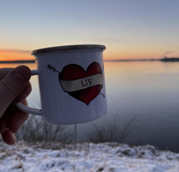 Kop i front med varm kakao og udsigt over Lillebælt i baggrunden hvor solen går ned