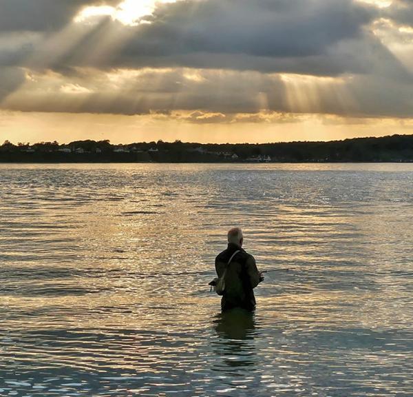 Lystfisker nyder solnedgangen i Strib